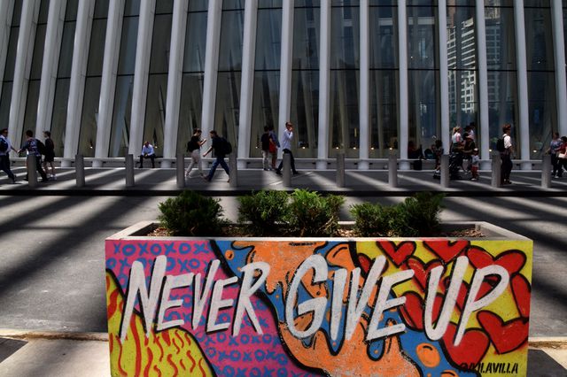 A photo of graffiti reading "Never Give Up" near the World Trade Center